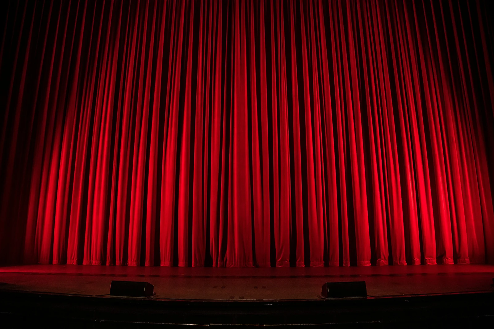 Glowing red theater curtain lit by stage lights